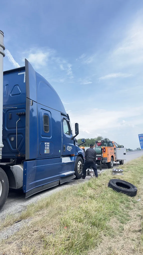 Roadside assistance being performed on a blue semi truck