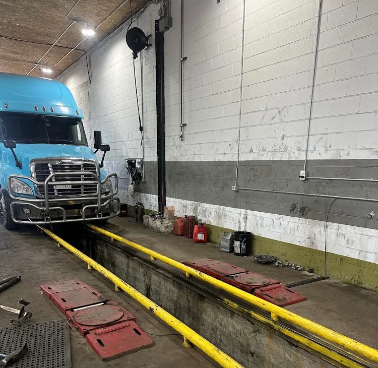 Blue semi truck positioned over shop service pit